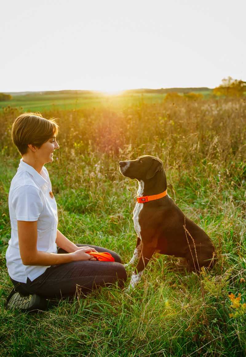 Robine Klinner sitzt entspannt mit einem Hund im Gras